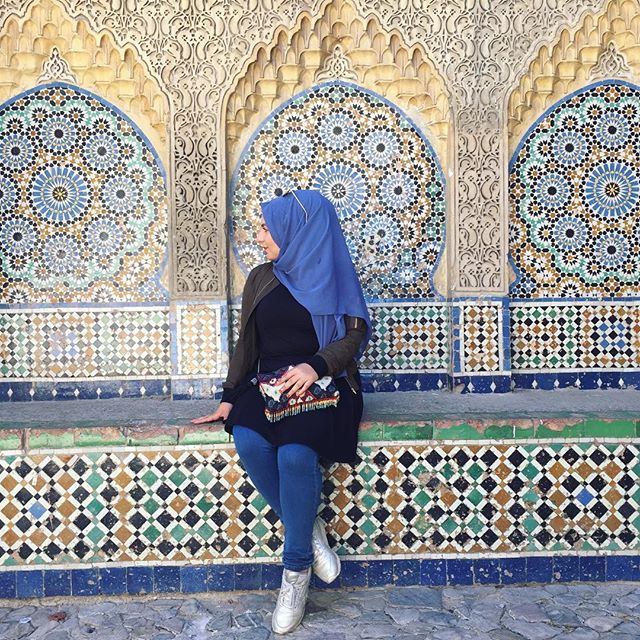 Auf dem Bild bin ich sitzend abgebildet. Dieser Platz befindet sich in der nähe der Kasbah von Tangier und hat wunderschöne Wandverzierungen in vielen verschiedenen Farben wie blau und grün gehalten.