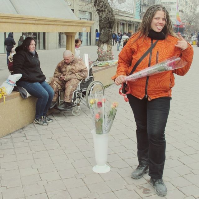 Rosenverkäuferin in der Almatiner Fußgängerzone posiert mit einer Rose in der Hand.
