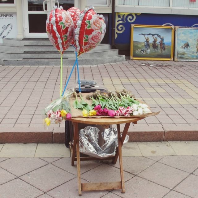 Tisch in der Fußgängerzone auf dem Tulpen und herzförmige Heliumluftbalons angeboten werden