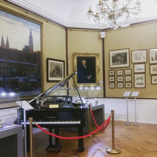 Screenshot_20170312-101726_1 Raum im historischen Museum im Stadtpalast von Wroclaw. Zu sehen ist ein Flügel, an der Wand hängen verschiedene Gemälde.