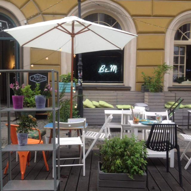 Die Terrasse eines Cafés, mit sonnenschirmen, Tischen und Stühlen und unvollendet liebevollen details und vor allem mit vielen frischen Pflanzen