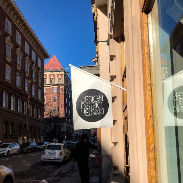 An ein Geschäft hängt ein Fähnchen, welches den Schriftzug "Design Distric Helsinki" trägt