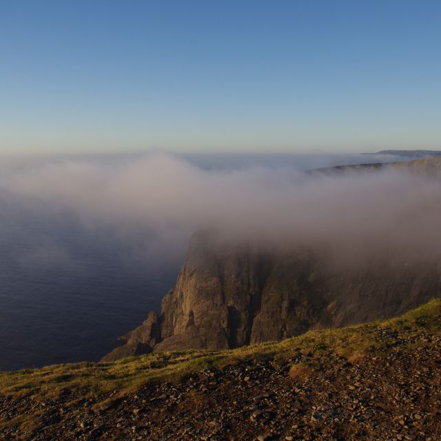 Wolke legt sich um den Gipefel eines Fjordes