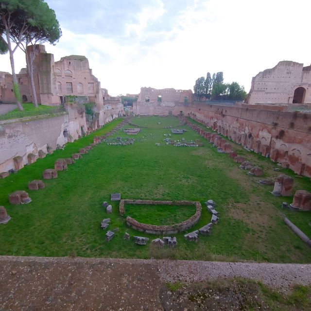 Das antike Stadion auf dem Palatin. Eingefasst von hohen Mauern erkennt man eine Rasenfläche mit verschiedenen Markierungen aus Steinen.