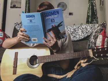 Frau mit Gitarre und Finnischbuch