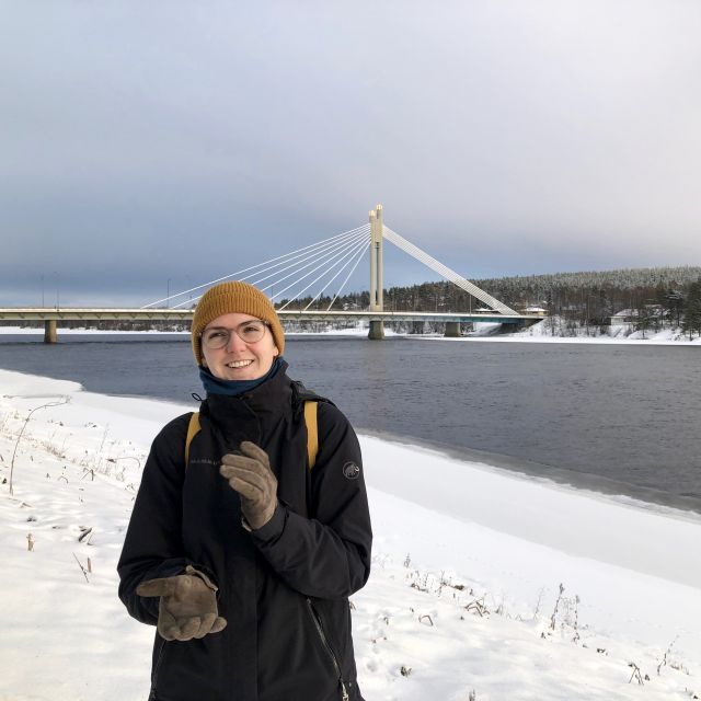 Frau in Winterkleidung vor FLuss mit Brücke