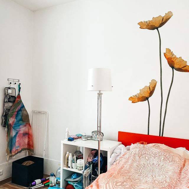 Zimmer mit Bett und Mohnblumen an der Wand.