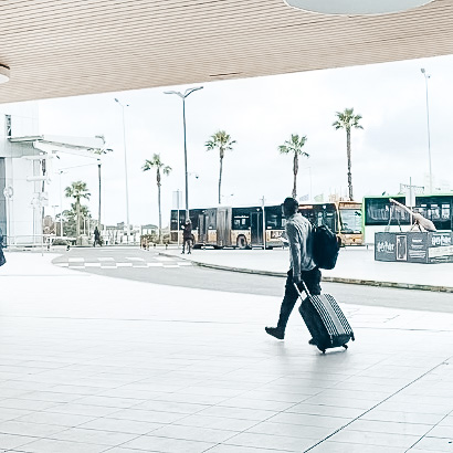 Mensch mit Koffer, im Hintergrund Palmen.