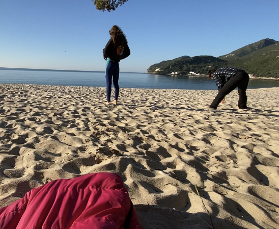 Zwei Menschen machen Yoga am Strand.
