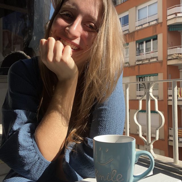 Ein Mädchen das ,ist einer Tasse Kaffee in der Sonne sitzt