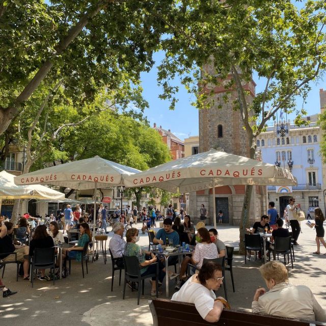 Ein kleiner Platz in Barcelona, an dem Menschen an kleinen Tischen und auf Bänken sitzen.