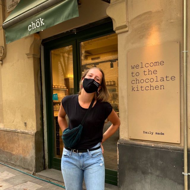 Ein Mädchen, das kit Maske vor einem Restaurant steht.