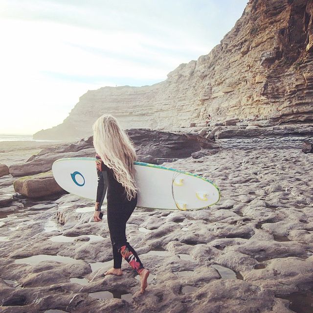 Frau mit Surfbrett am Meer.