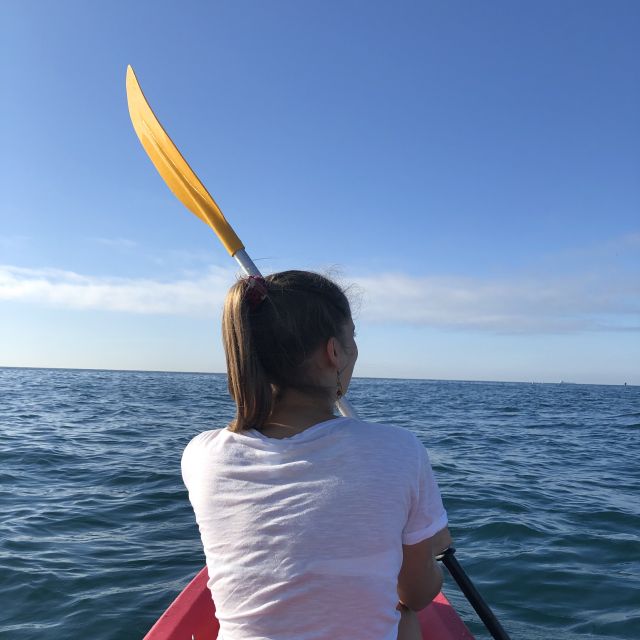 Ein Mädchen auf dem Meer, in einem Kayak und mit Paddel.