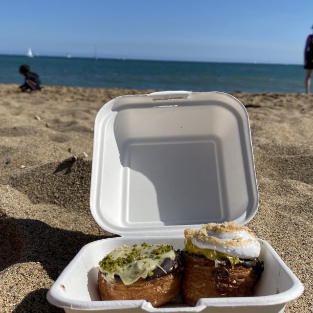 145d608b-f080-4832-9ed9-1191d8169336 Eine Box mit Cronuts am Strand.
