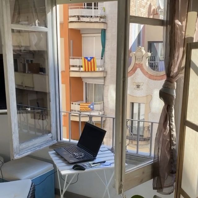8e1c8667-9483-4be5-b526-96c43f642ed3 Ein Laptop, der auf einem kleinen Tisch vor einem Fenster steht.