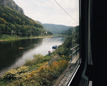 Blick aus dem Zugfenster auf einen Fluss und Berge