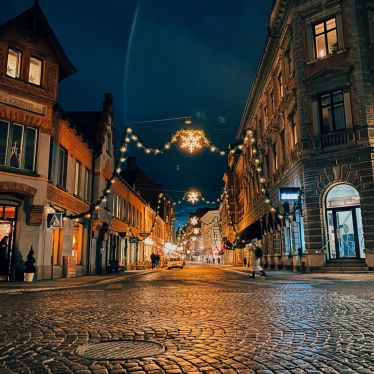 Eine Kopsteinpflasterstraße ist zur Weihnachtszeit fetslich geschmückt mit zahlreichen Girlanden, Sternen und Tannenzweigen.