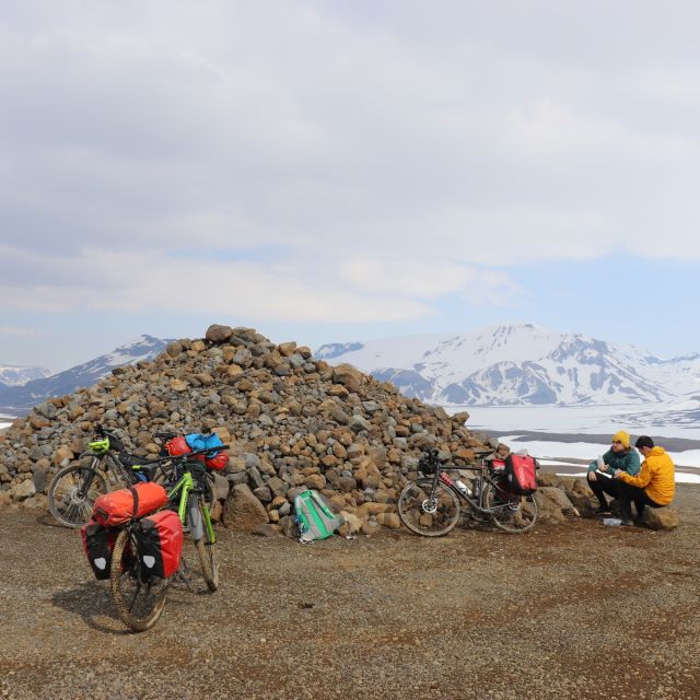 Zwei Menschen essen in den isländischen Highlands. Drei Fahrräder sind zu sehen.