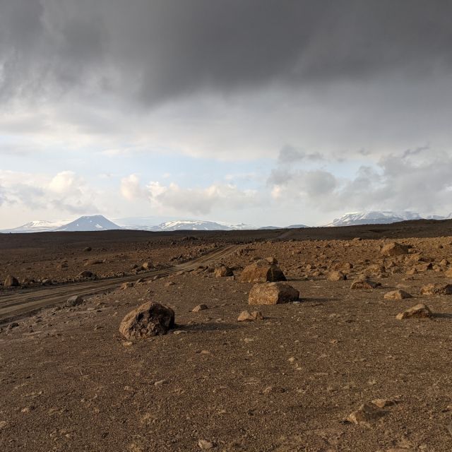 Landschaft in den isländischen Highlands. Es ist Felsig und im Hintergrund sieht man Berge.