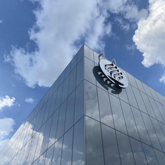 Gebäude mit dem Logo der Universität, Wolken spiegeln sich im Gebäude