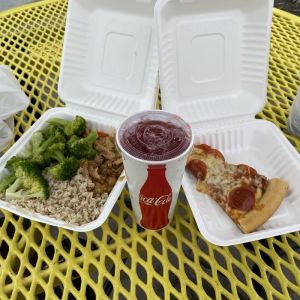 Campus-Essen mit einem Stück Pizza, Broccoli, Reis und einem Getränk