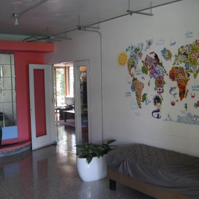 Ein großer Eingangsbereich mit einem kleinen Sofa, einem Spiegel und einer künstlerisch gestalteten Weltkarte an der Wand.
