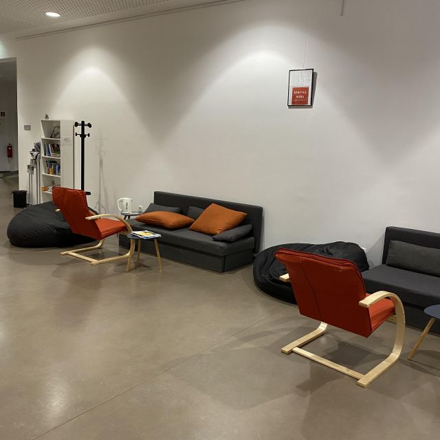 Zwei dunkelgraue Sofas und zwei rote Sessel entlang einer weißen Wand aufgestellt.