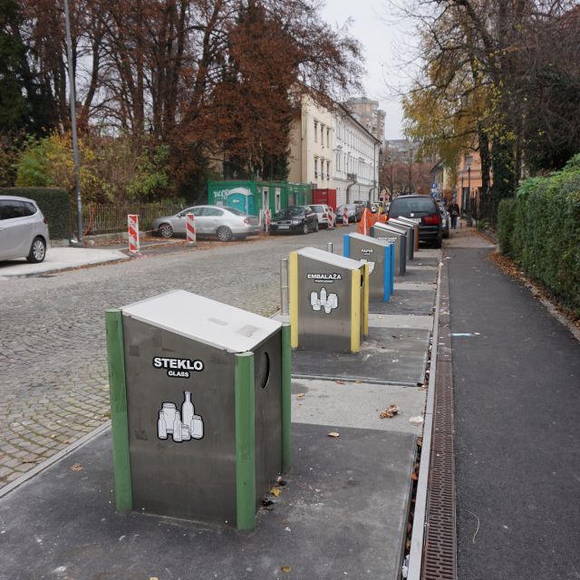 Bunte Recyclingtonnen entlang einer Straße.
