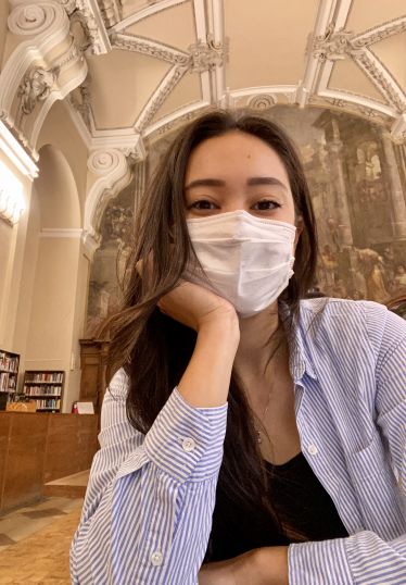 Studentin in der Bibliothek mit Maske