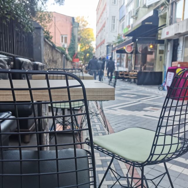 Einige Stühle stehen in einer kleinen Straße, in der es viele Cafés gibt.