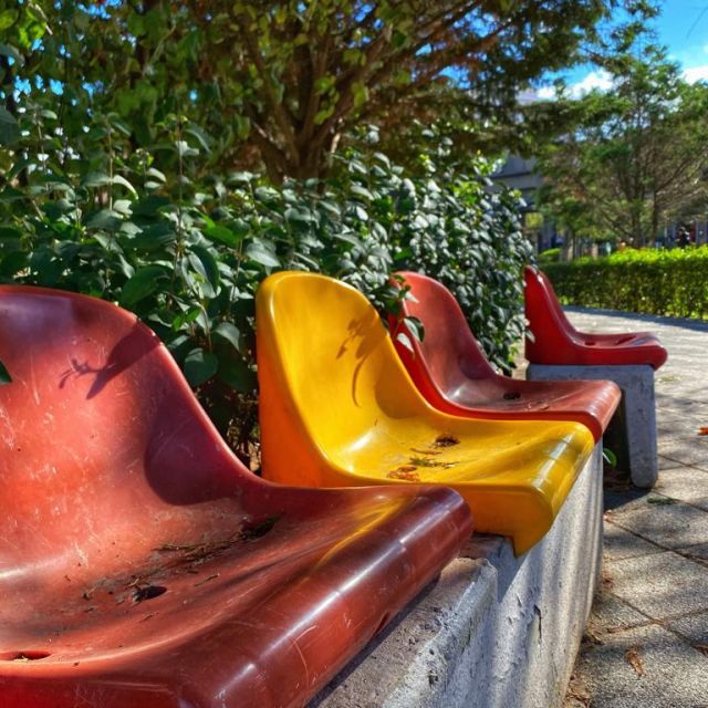 Rote und gelbe Plastiksitze in der Sonne.