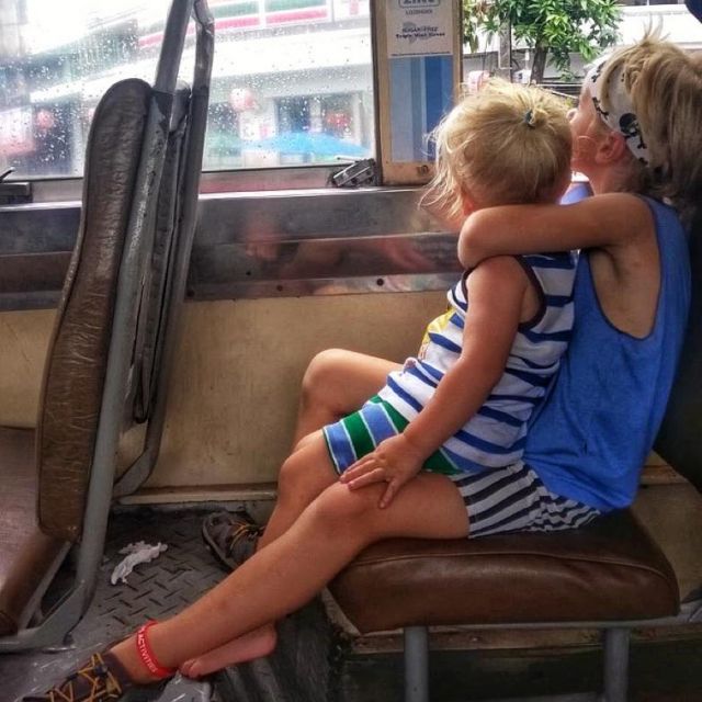 Sophies Kinder sitzen in einem Bus in Bangkok. Der ältere Sohn hält den jüngeren eng umschlungen.