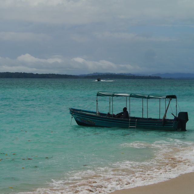 Ein kleines Boot direkt am Strand, zwischen türkisem Wasser und gelben Sand.