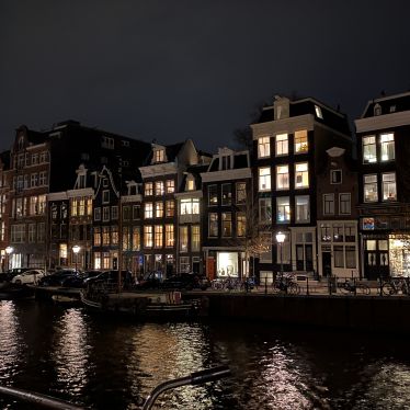 Man sieht eine Amsterdammer Gracht und Grachtenhäuser im Dunkeln.