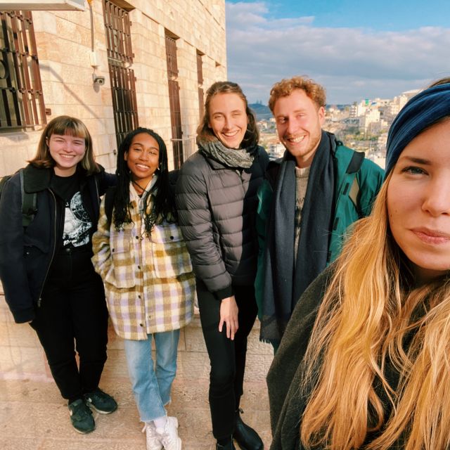 Auf dem Selfie ist Maja im Vordergrund zu sehen. Links von ihr sind vier Personen abgebildet und im Hintergrund ein Gebäude.