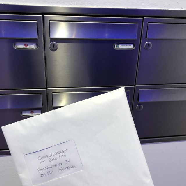 Briefumschlag mit den Visumsdokumenten vor dem Briefkasten des Konsulats