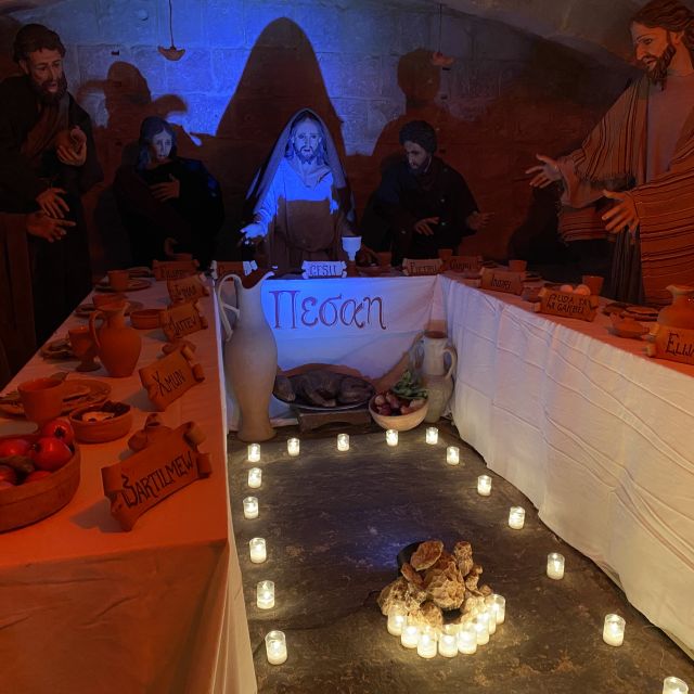 Statuen, die Jesus und seine zwölf Jünger darstellen, sitzen an einem Tisch. Auf dem Tisch stehen Speisen und vor dem Tisch sind Kerzen aufgestellt.