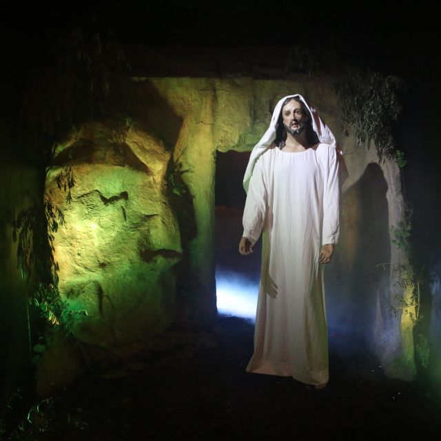 Eine weiß gekleidete Jesus Statue steht vor einem Steingrab und ist umhüllt von Nebel.