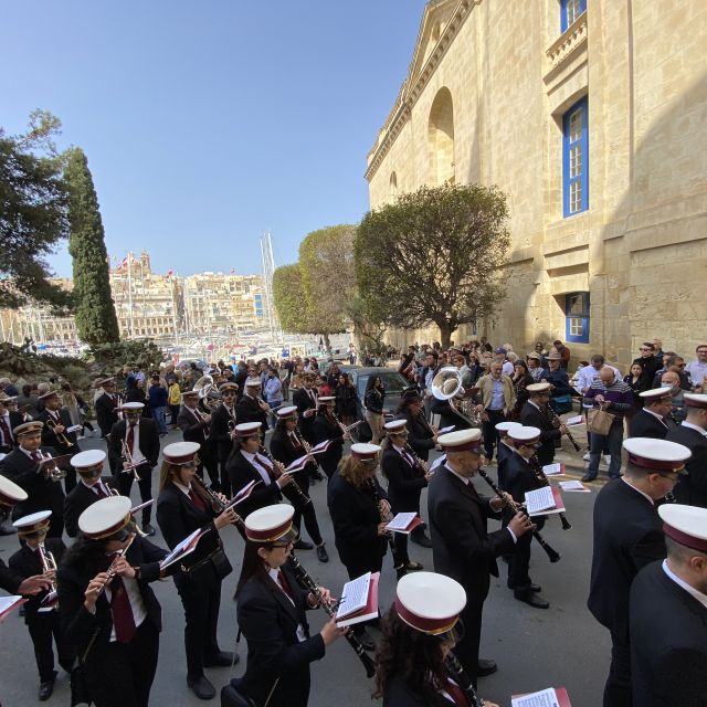 Auf einer Straße spielen viele Musiker in feierlicher Uniform Instrumente.