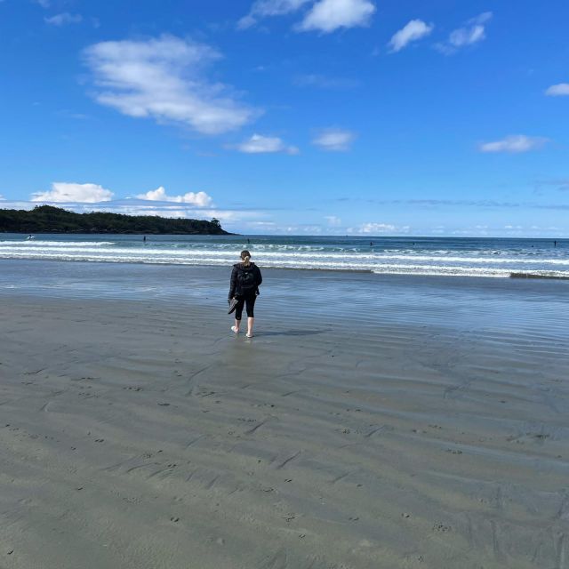 Strand, blauer Himmel, ein Mädchen mit Rucksack läuft am Strand entlang