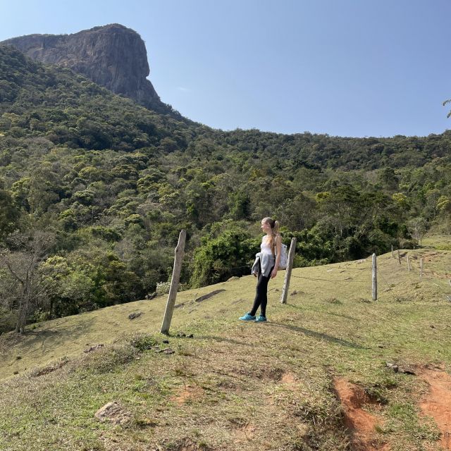 Ein Mädchen steht auf einem Wanderweg, im Hintergrund Wald und ein großer Felsen.