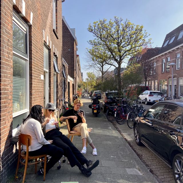 Zwei Jungs und ein Mädchen sitzen vor einem Hauseingang, Sonnenstrahlen fallen auf ihre Gesichter, Häuser im holländischen Baustil im Hintergrund zu erkennen