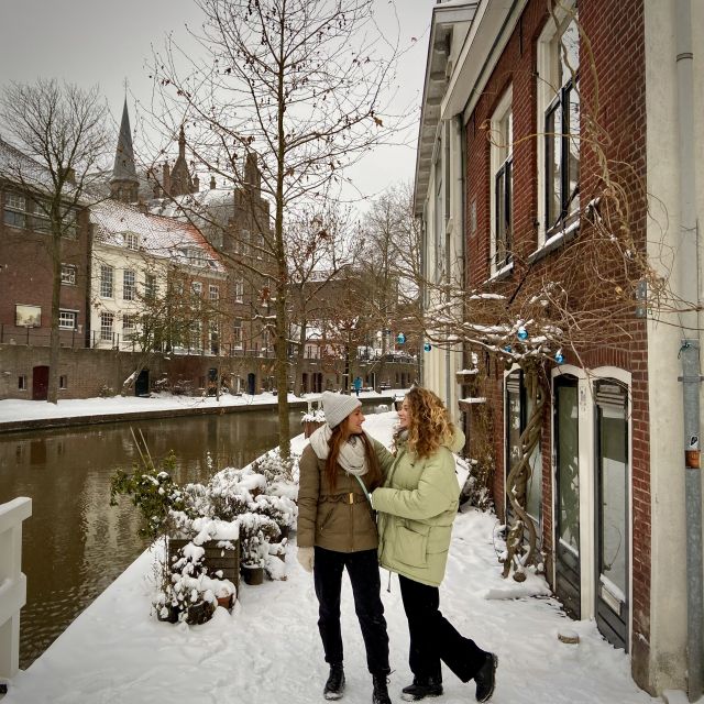 zwei lächelnde Mädchen, Häuser im holländischen Baustil im Hintergrund zu erkennen, Kanal, winterliche Atmosphäre, Schnee