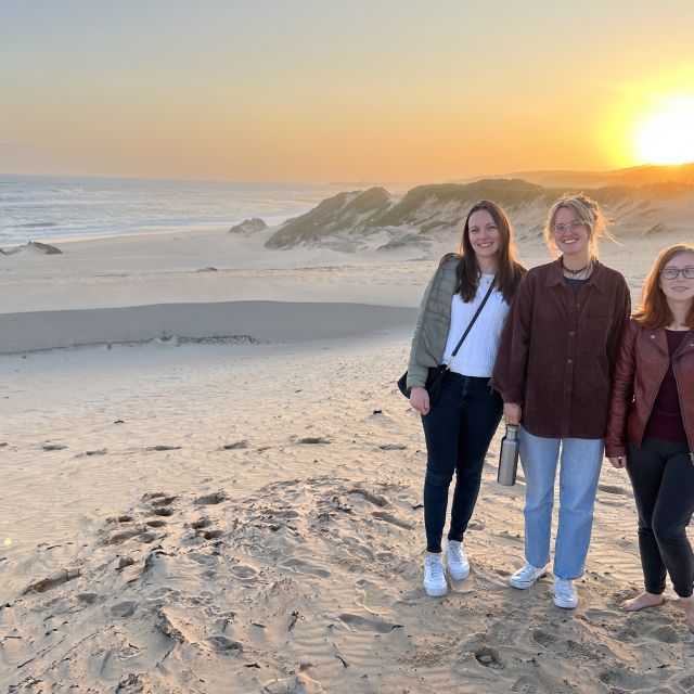 Drei Freundinnen zusammen bei einem Sonnenuntergang am Strand.