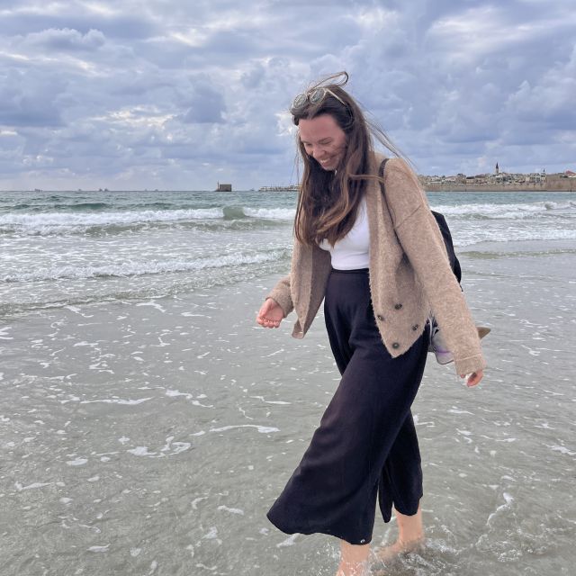 Sarah mit langer weiter Hose, T-shirt und Strickjacke am Strand