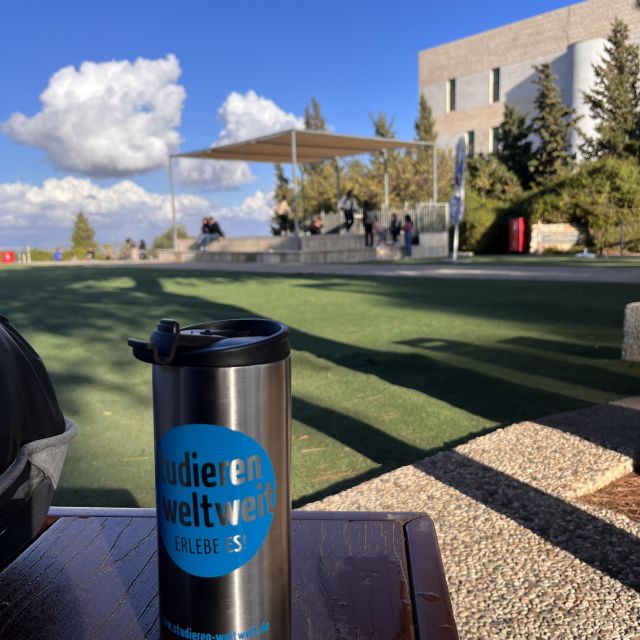 Studieren Weltweit Kaffeebecher im Vordergrund, im Hintergrund der Campus der Uni Haifa