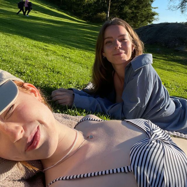 Selfie mit mir im Vordergrund im Bikini auf einer Wiese liegend. Im Hintergrund meine Freundin.
