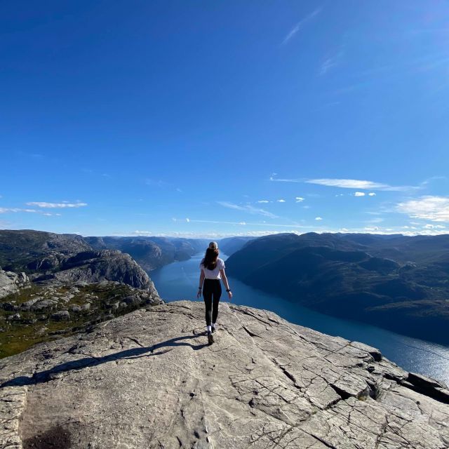 Ich laufend von hinten auf einem Felsvorsprung, im Hintergrund ein Fjord