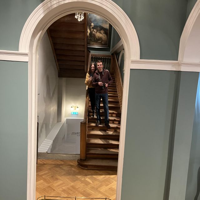 Mann und Frau stehen auf einer Treppe und machen ein Selfie in einem Spiegel im Kunstmuseum